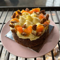 Small cake with white frosting, carrots, and nuts on a pink plate.