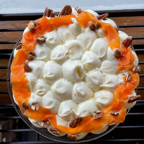 Decorative cake with white frosting, orange decorations, and pecans.